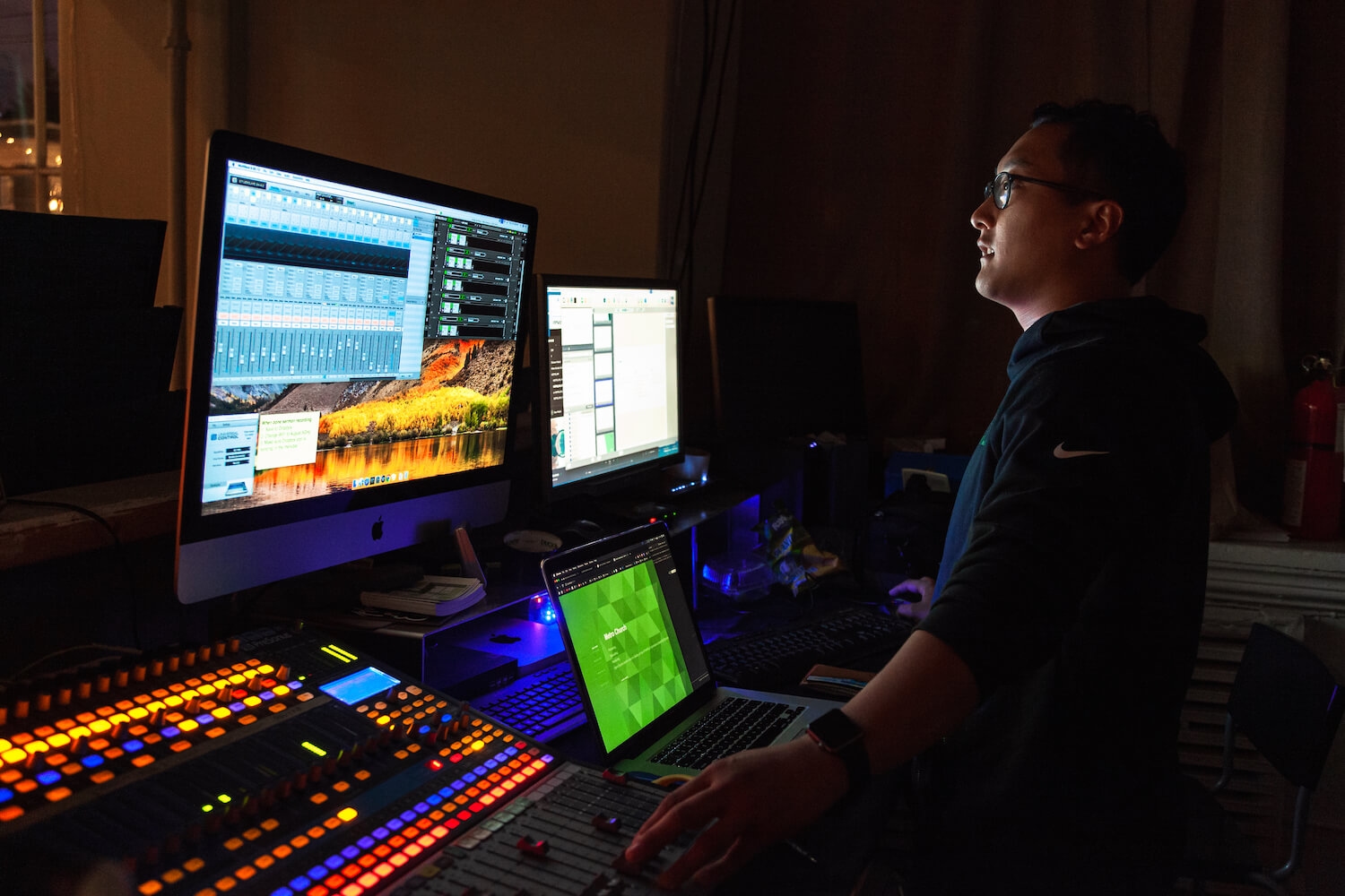 A church member in a low-light setting, with computer monitors.